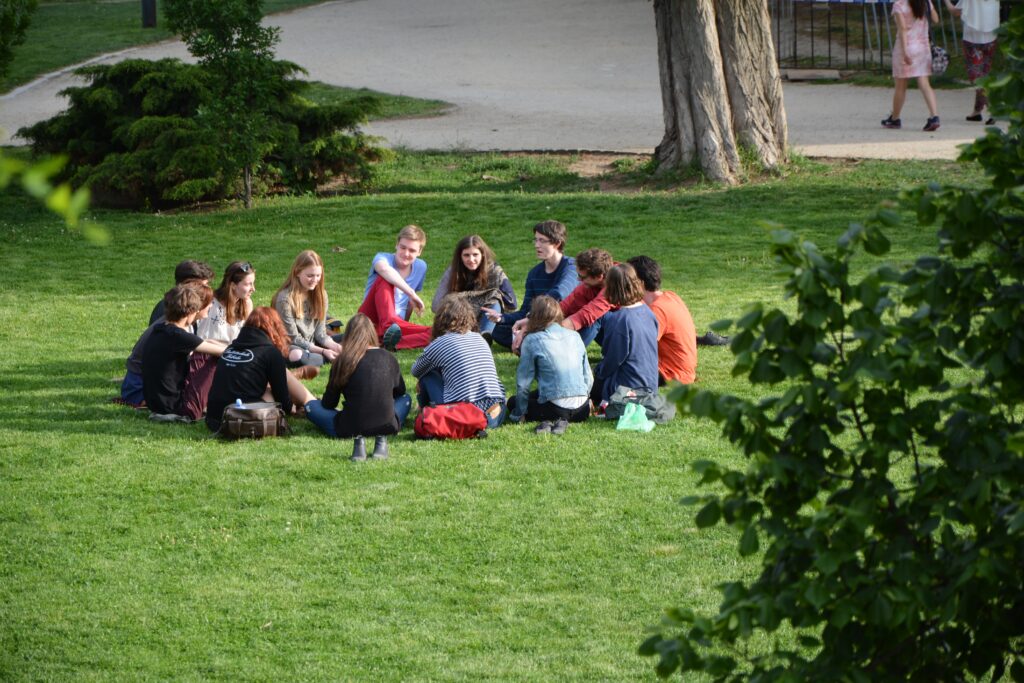 A group of people sitting on the grass in a circle.